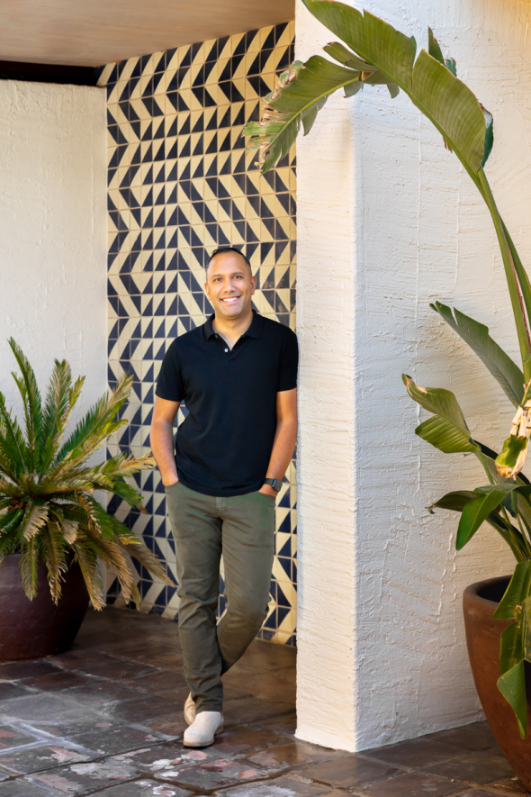 A man standing in front of a wall with a plant