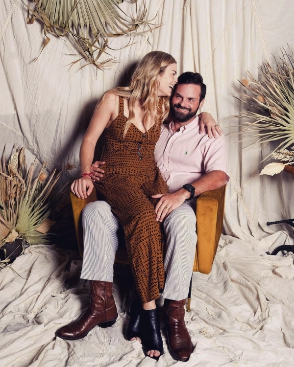 A man and woman sitting on a bed.